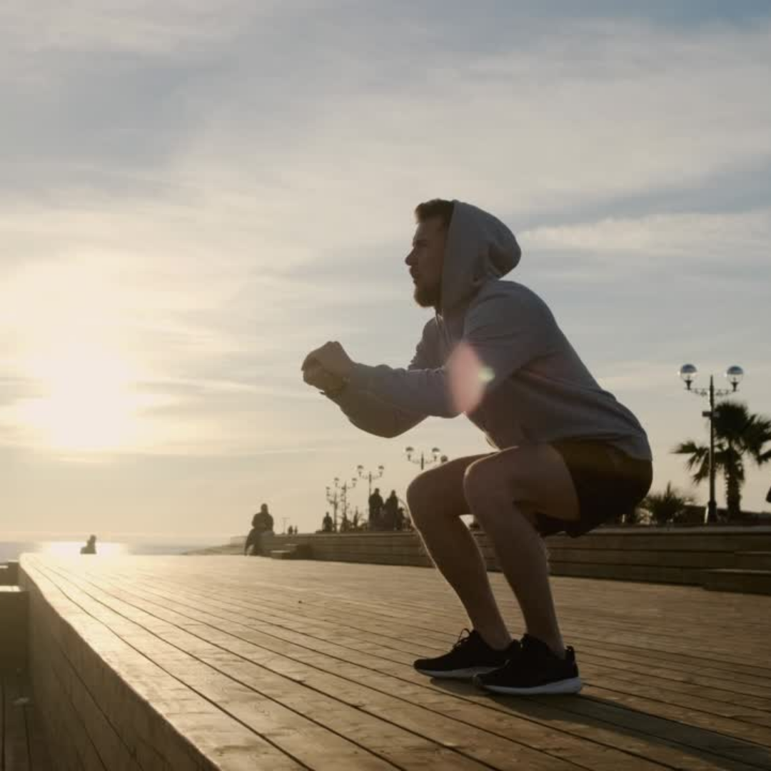 Ein Mann führt eine Kniebeugeübung im Sonnenuntergang durch.