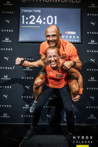 Zwei Athleten vom Mein CLUB Burghausen feiern ihren Erfolg beim HYROX Cologne Wettkampf.