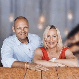 Andrea und Alex Gaugler, Gründer von Mein CLUB Burghausen, lächeln an einem Holztresen.