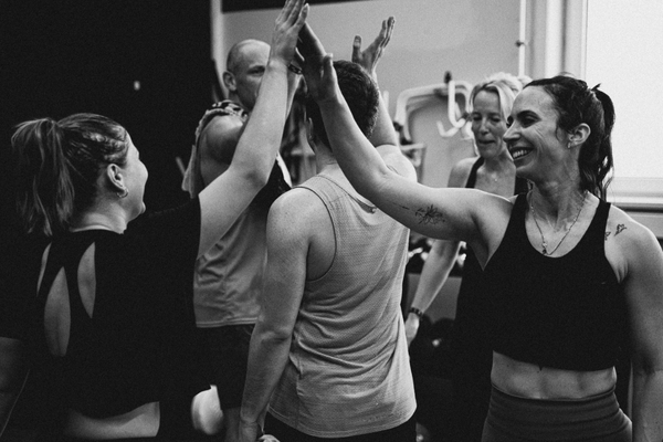 Trainingsgruppe im Mein CLUB Burghausen feiert gemeinsam mit High-Fives nach dem Workout.