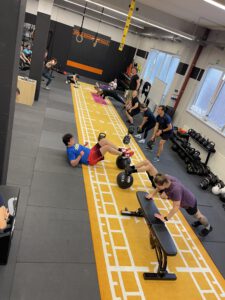 Teilnehmer absolvieren ein funktionelles Zirkeltraining mit Kettlebells und Eigengewichtsübungen.