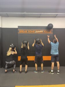 Vier Mitglieder des Mein CLUB Burghausen führen Wall Balls an der Trainingswand aus.