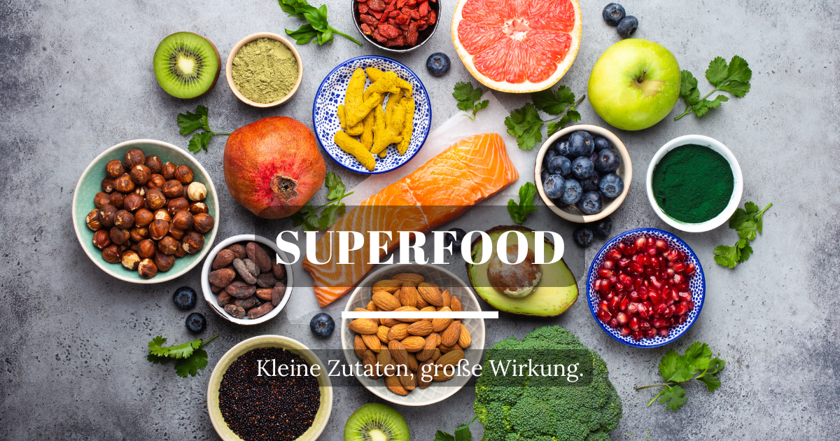 Auswahl an nährstoffreichen Superfoods wie Beeren, Nüssen, grünem Blattgemüse und Samen auf einem Tisch.